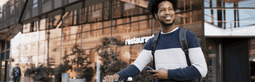 Jovem atravessa o passeio com uma trotinete elétrica na mão