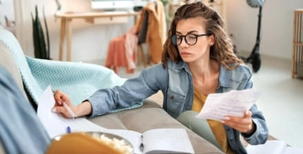 Jovem mulher sentada no chão da sala ocupada a organizar os documentos.