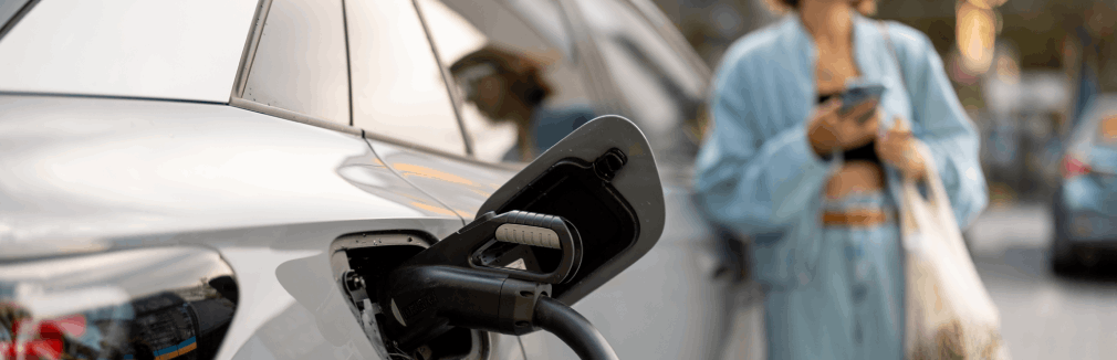 Rapariga aguarda num ponto de abastecimento por carregamento carro elétrico.