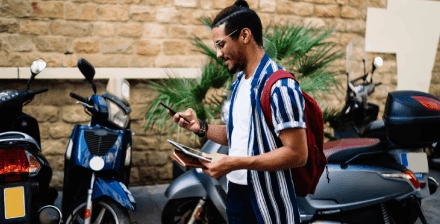 Homem jovem a pesquisar no telemóvel para comprar uma moto usada.